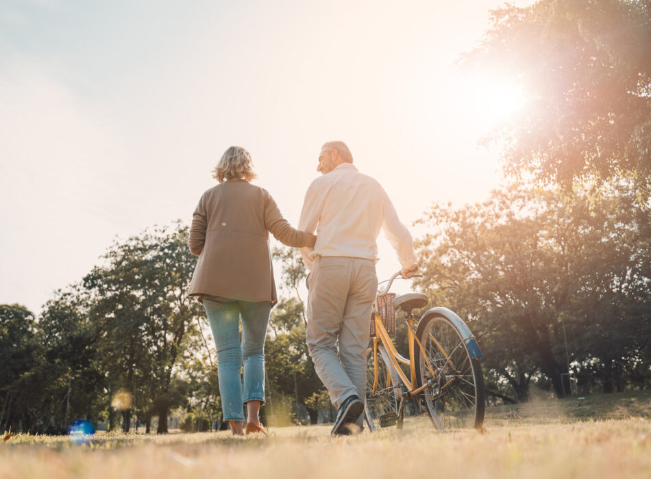 Beautiful,Senior,Couple,Walking,Their,Bike,Along,Happily,Talking,In